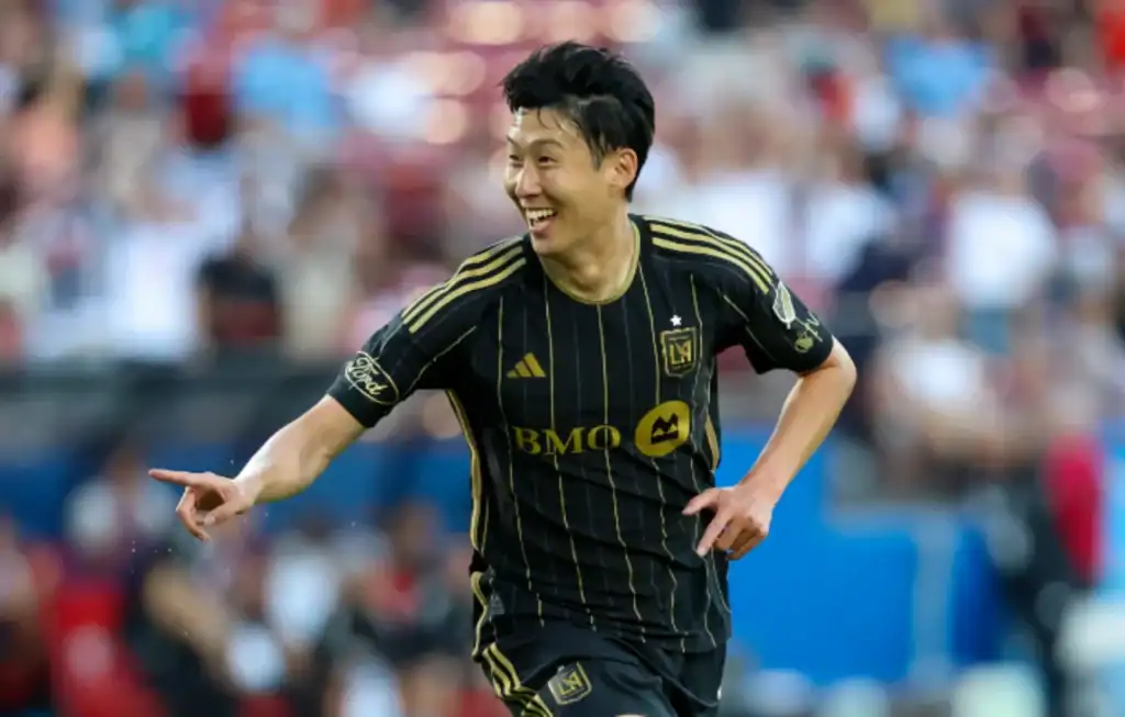 스포츠중계 MLS LAFC의 손흥민이 득점 직후 환하게 웃으며 손가락으로 가리키는 골 세리머니 모습, 팀 동료와 팬들이 열광하는 순간