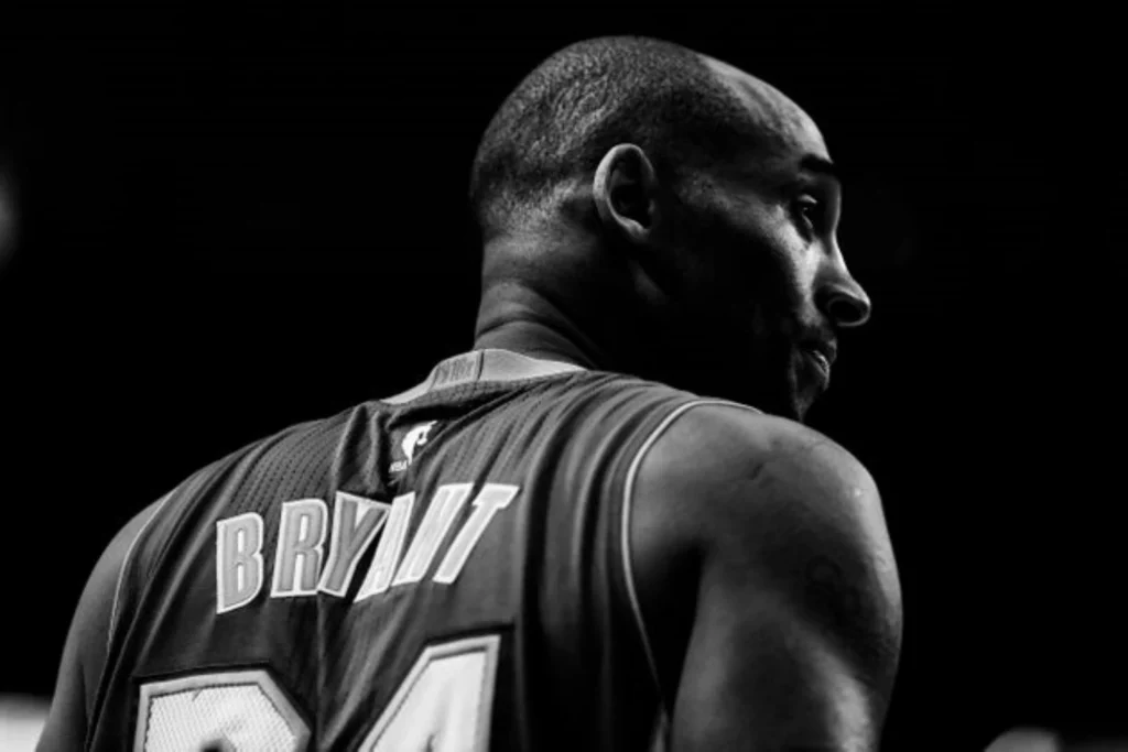 NBA 레전드 코비 브라이언트가 등번호 24번 유니폼을 입고 코트 위에 서 있는 흑백 사진